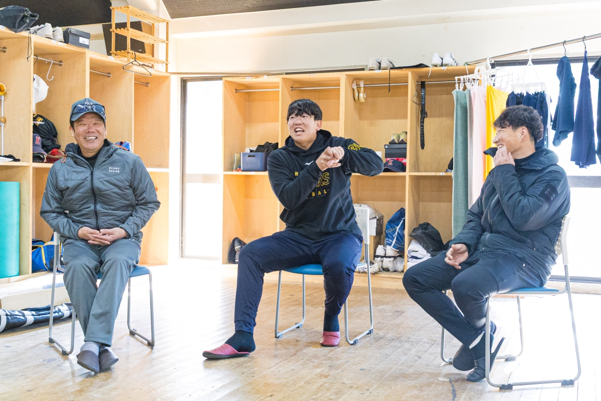 ドアの開け方を実演する畠選手と笑っている藤井コーチ、小深田選手