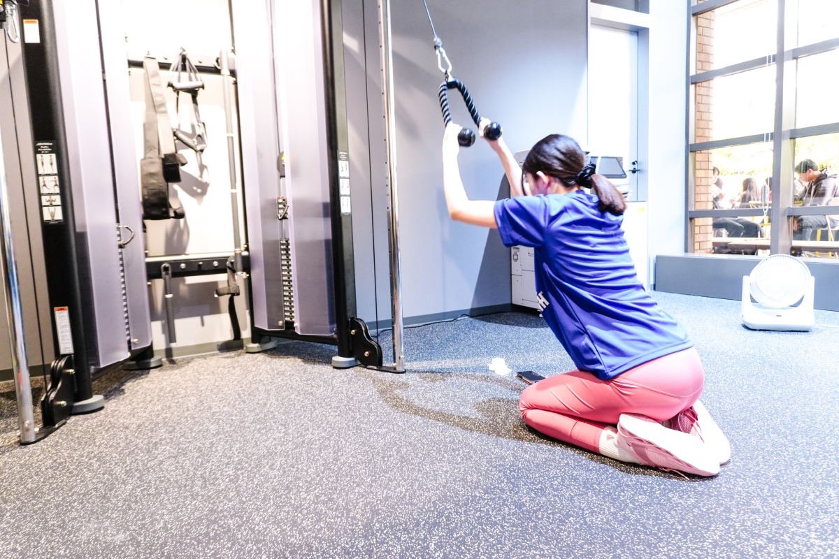ケーブルマシンを使ってトレーニングをする女子学生の写真