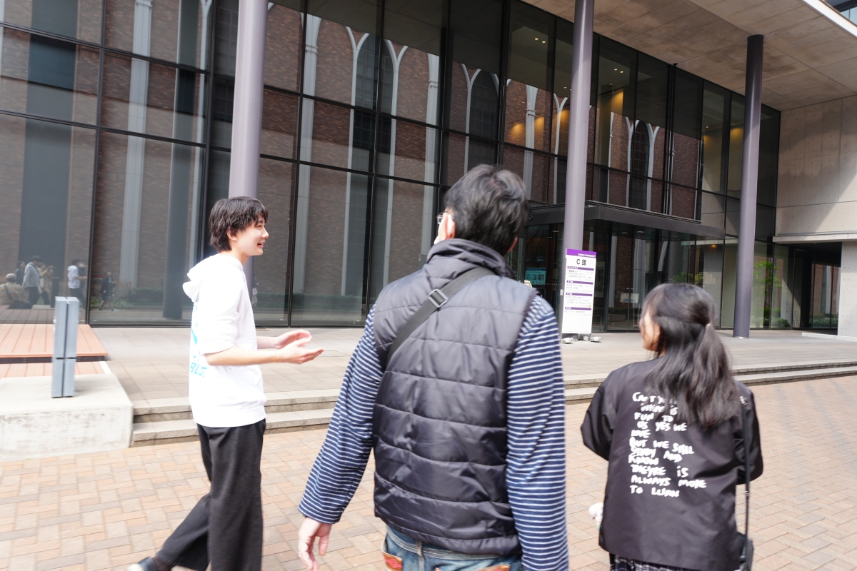 桝田さんが来場者の親子を法学部棟へ案内する様子