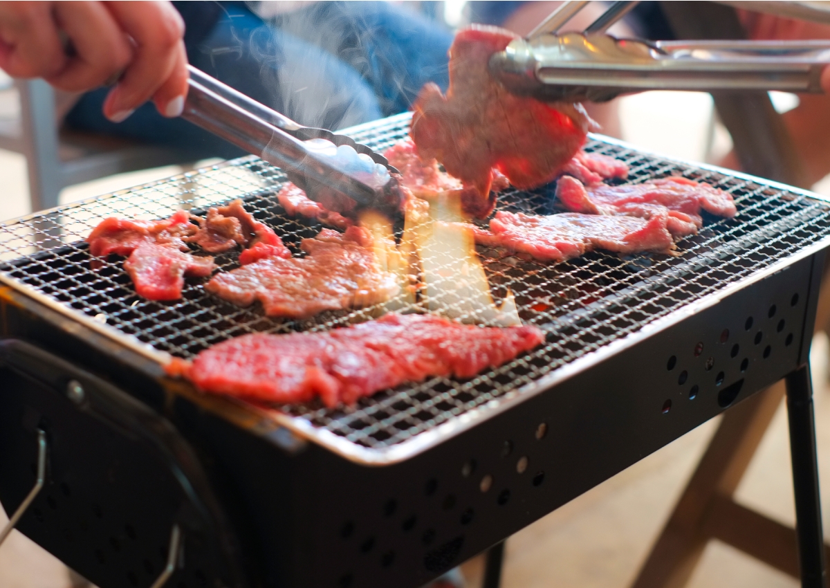 バーベキューでトングを使って肉を焼くイメージ