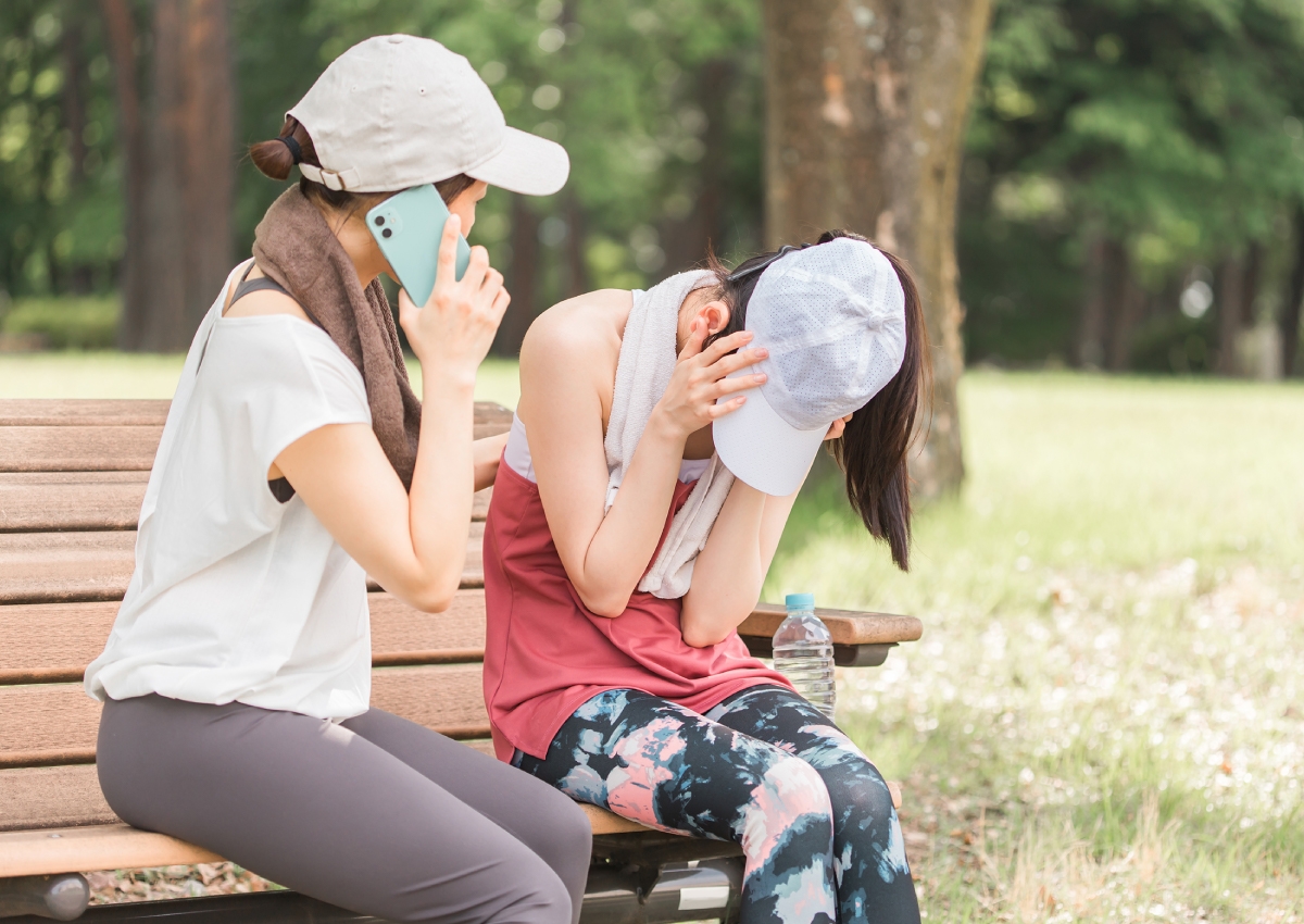熱中症疑いの人と救急車を呼ぼうとしている人のイメージ